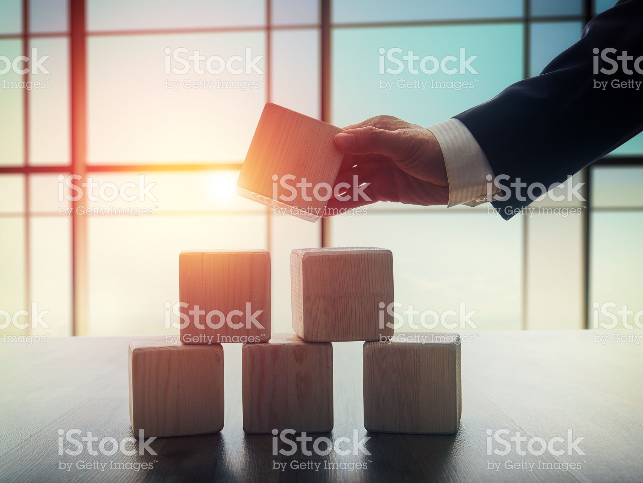 The concept of planning in business. Wooden cubes on a desk in the office. The concept of leadership. Hand men in business suit holding the cubes.